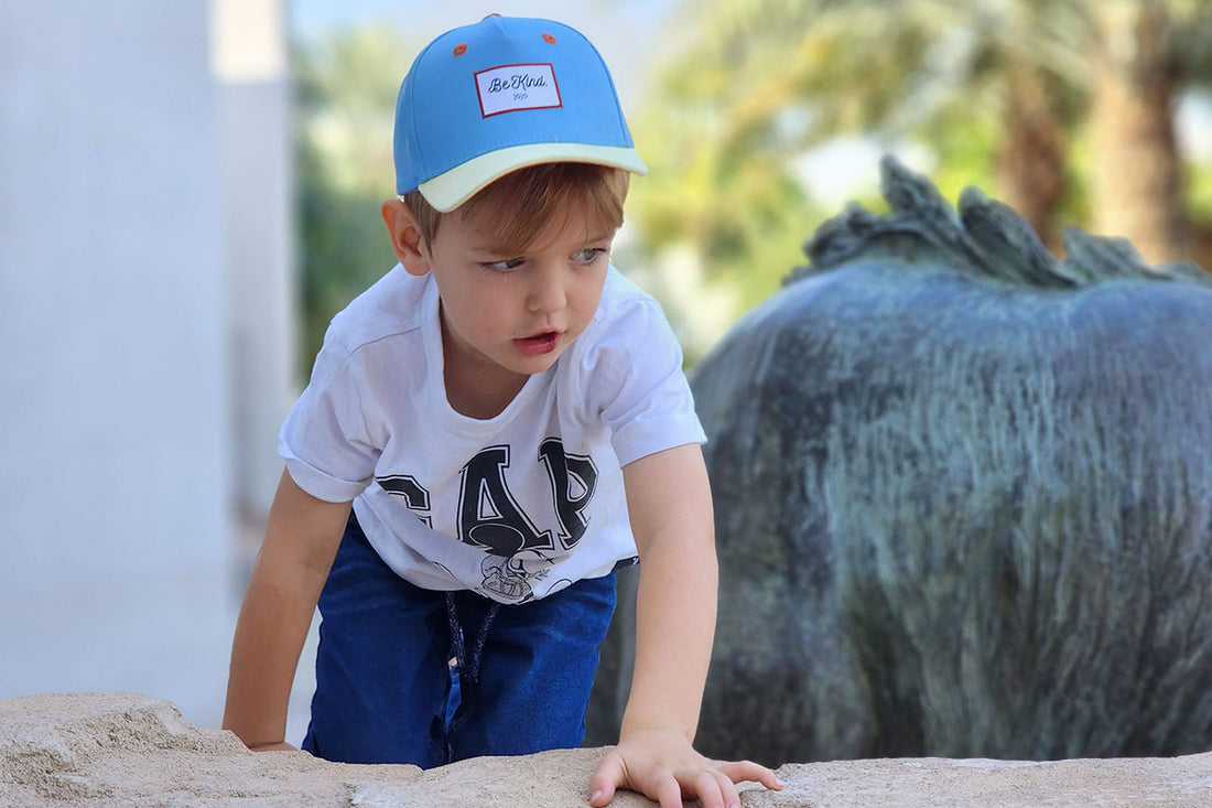 A kid in a cool hat blimbs a wall.