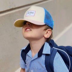 A cool kid walks to school in a baseball cap.