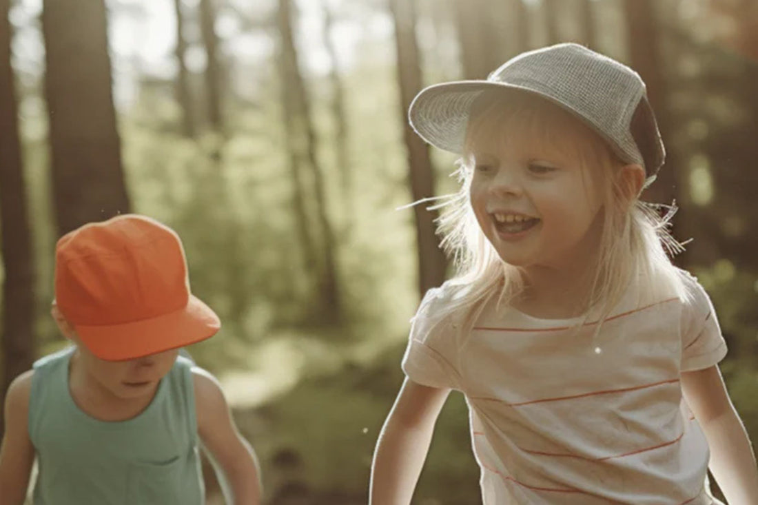 Two kids in hats play in the woods.