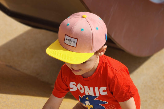 A cool kid plays in a lovely pink hat.