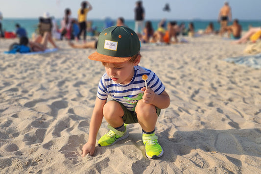 A child in a sun hat plays on the beach.